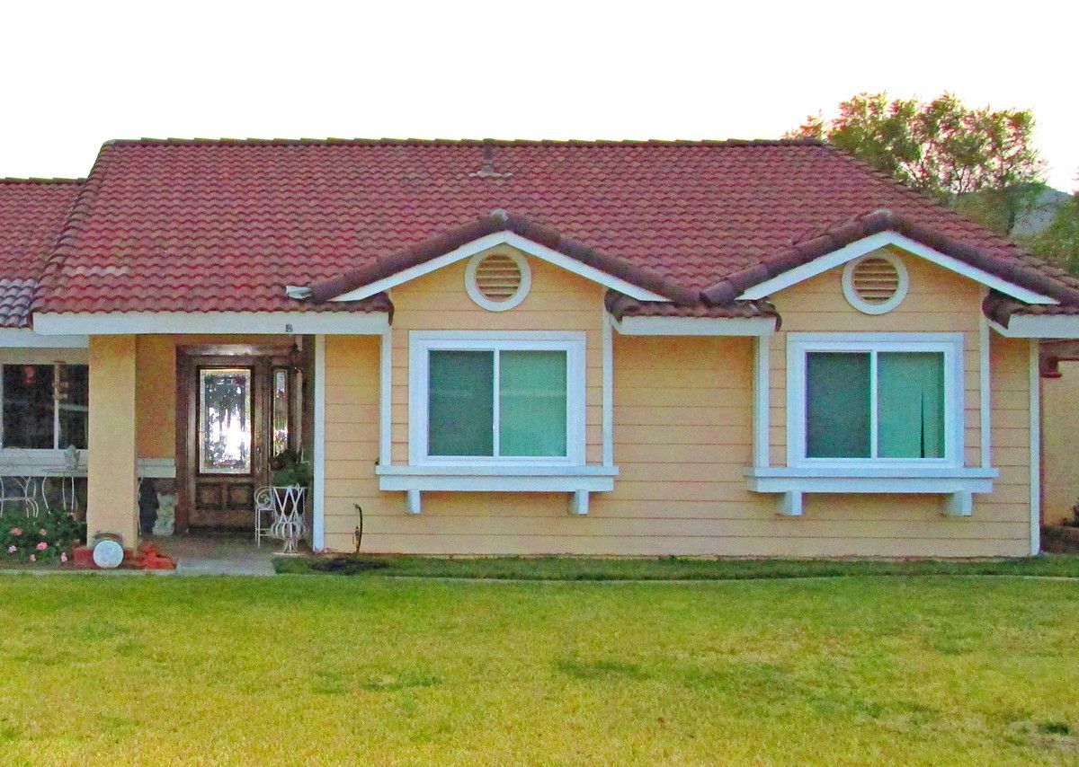 Single-story yellow house with red roof and front lawn