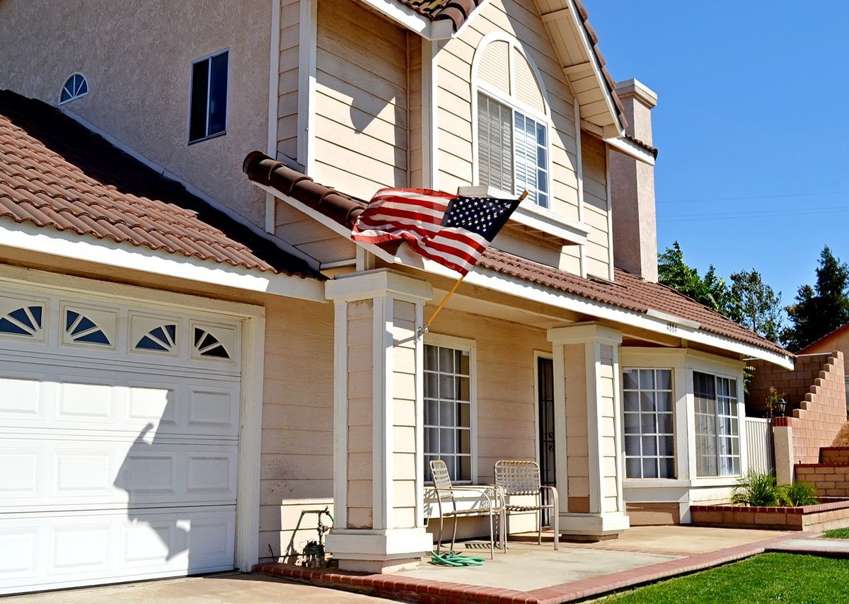 Two-story suburban house with a garage and an American flag over the front porch