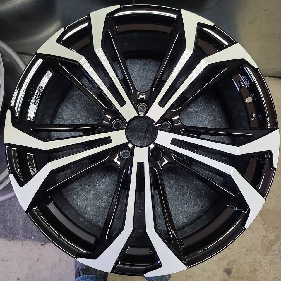 Black and silver multi-spoke car wheel rim photographed against a light gray background