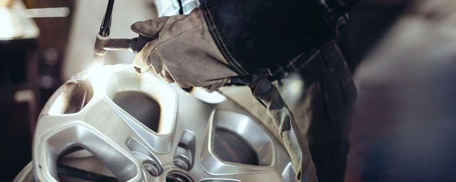 Close-up of a silver robotic face with a hand adjusting it in a dimly lit scene