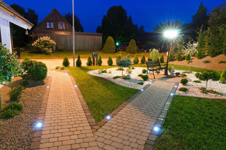 A brick walkway leads to a house at night