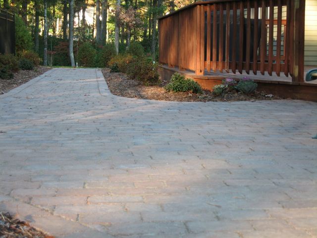 A driveway leading to a house with a wooden deck