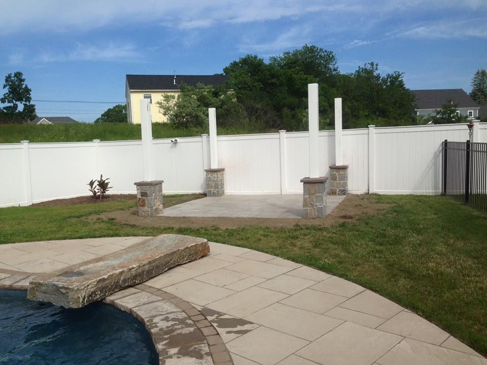 A white fence surrounds a swimming pool in a backyard