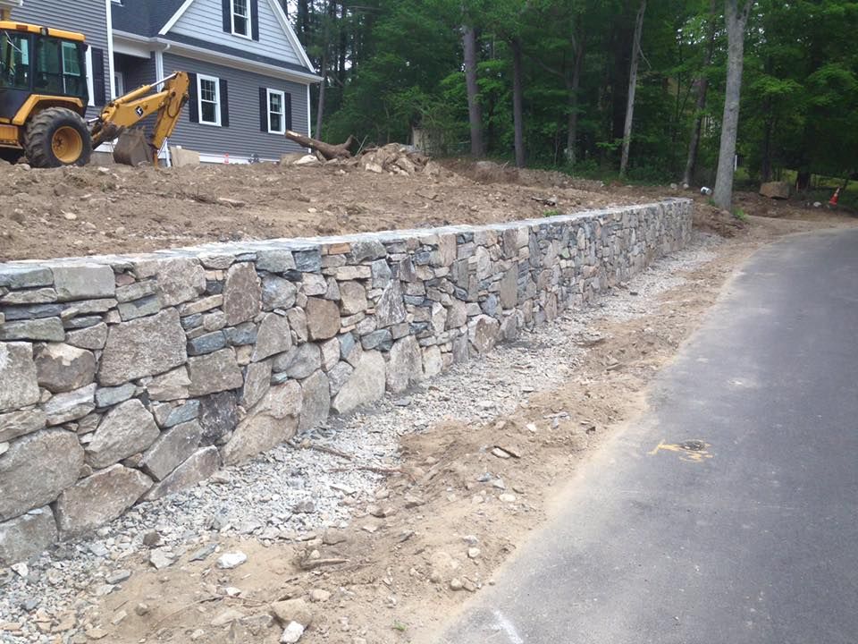 A stone wall is being built in front of a house