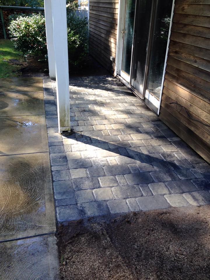 A brick walkway leading to a house with a sliding glass door.