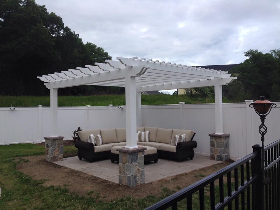 A pergola with a sectional couch underneath it