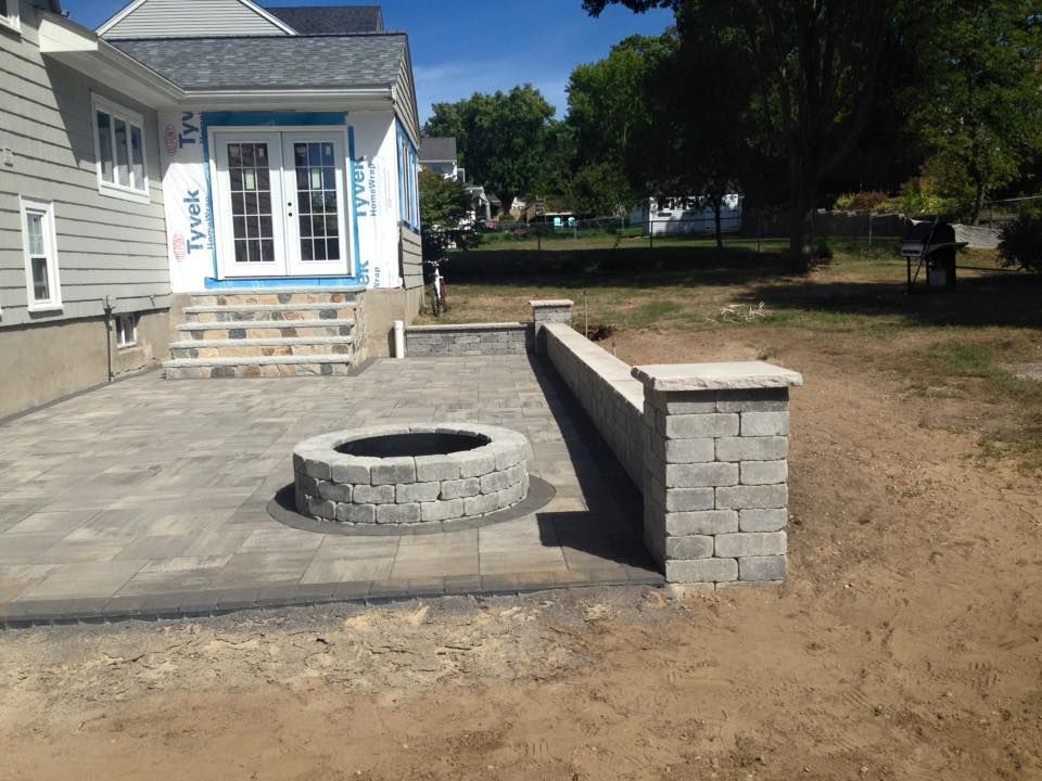 A fire pit is in the middle of a patio in front of a house