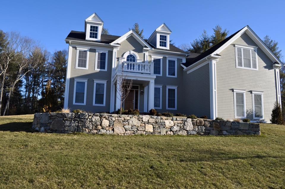 A large house with a stone wall in front of it