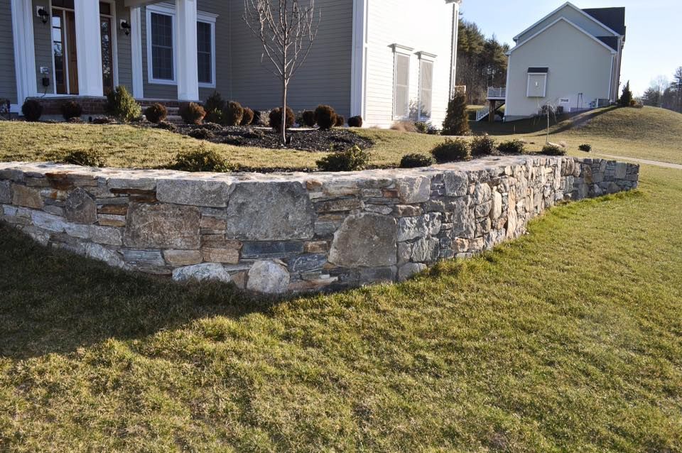 A house with a stone wall in front of it