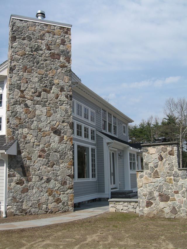 A large stone chimney on the side of a house