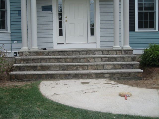 A blue house with stone steps leading up to the front door