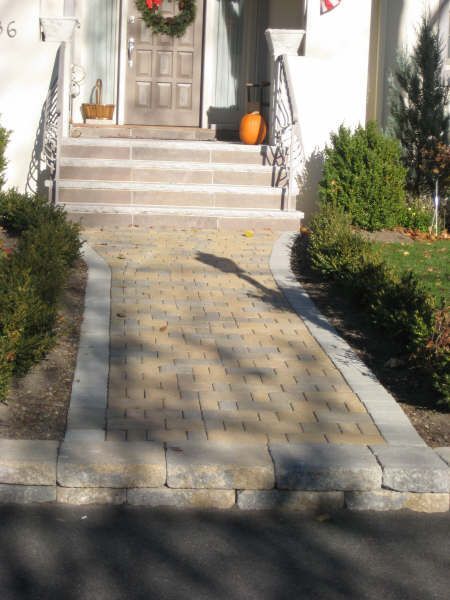 A brick walkway leading to the front door of a house