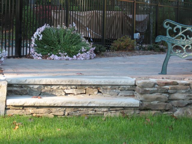A stone wall with steps and a bench in the background