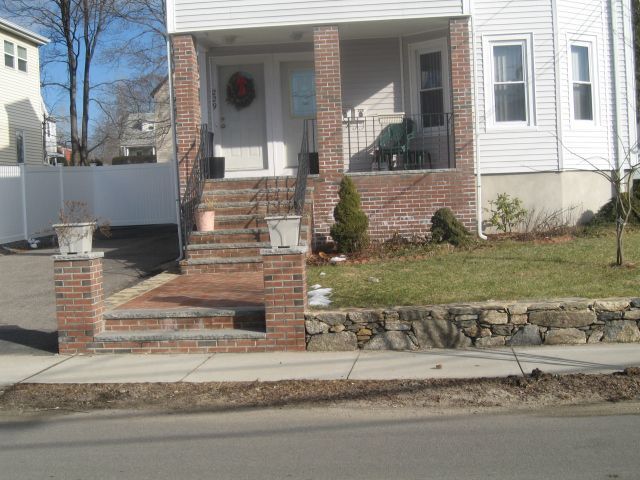 A white house with a brick porch and stairs