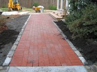 A red brick walkway is being built in front of a house.