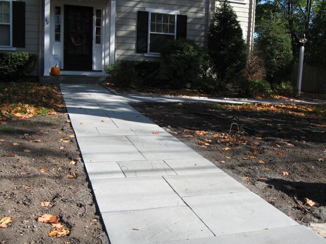 A concrete walkway leading to the front door of a house