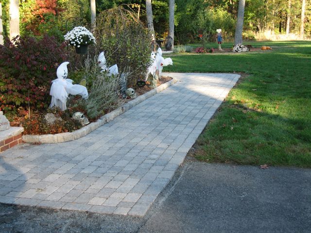 A brick walkway leading to a lush green yard