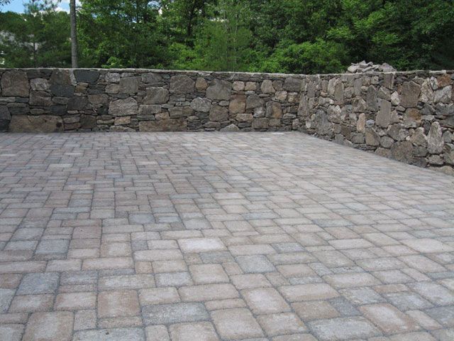 A brick patio with a stone wall in the background.