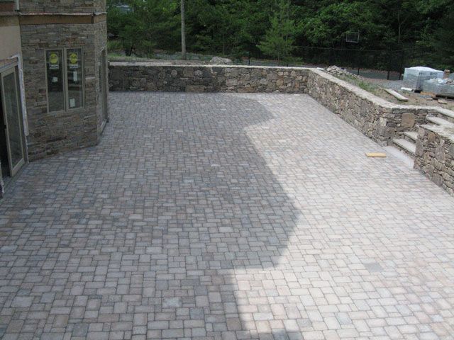 A brick patio with a stone wall surrounding it