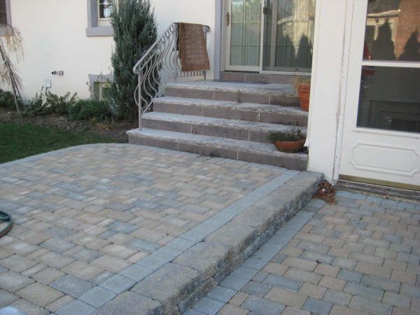 A brick patio with stairs leading up to a house
