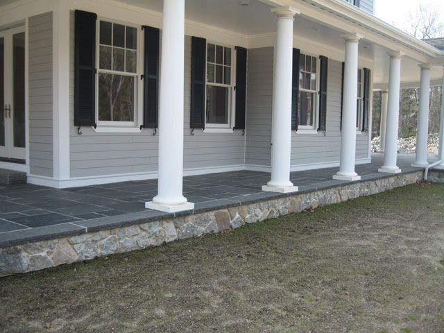 A porch of a house with white columns and black shutters
