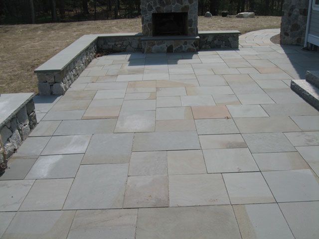 A patio with a stone fireplace in the background