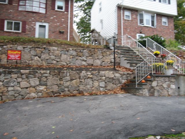 A stone wall with stairs leading up to a house