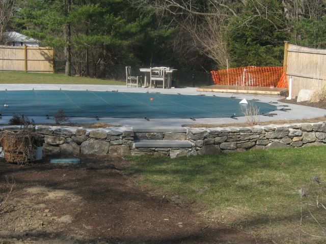 A swimming pool with a table and chairs in the background