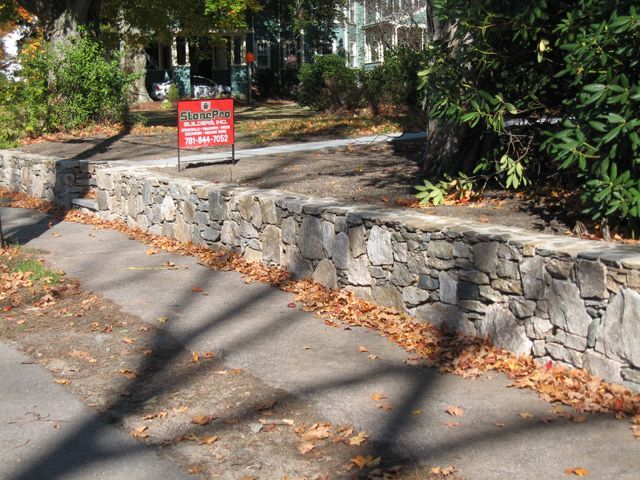 A stone wall with a for sale sign on it
