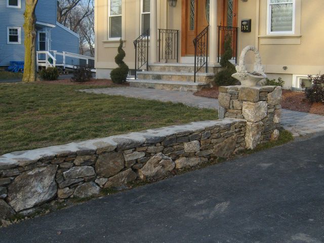 A house with a stone wall in front of it
