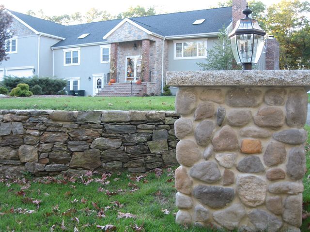 A large house with a stone wall in front of it