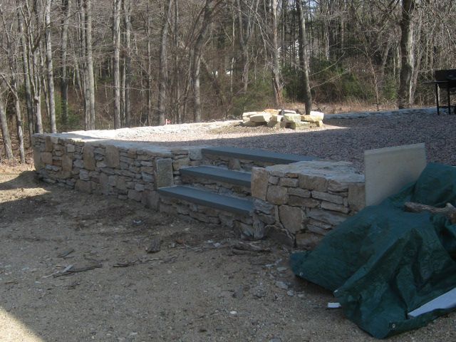 A stone wall with stairs and a green tarp on the ground
