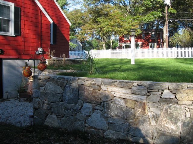 A red house with a stone wall in front of it