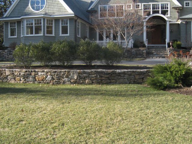A large house with a stone wall in front of it