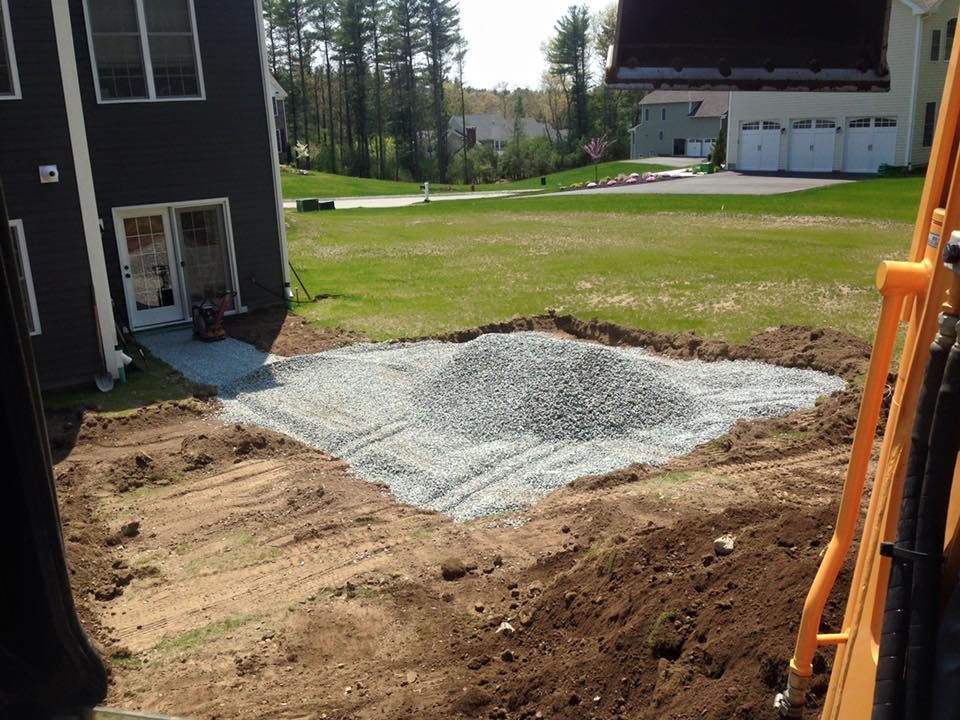 A pile of gravel is sitting in the dirt in front of a house.