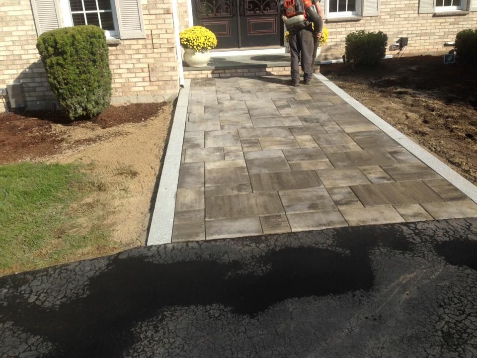 A man is standing on a brick walkway in front of a brick house
