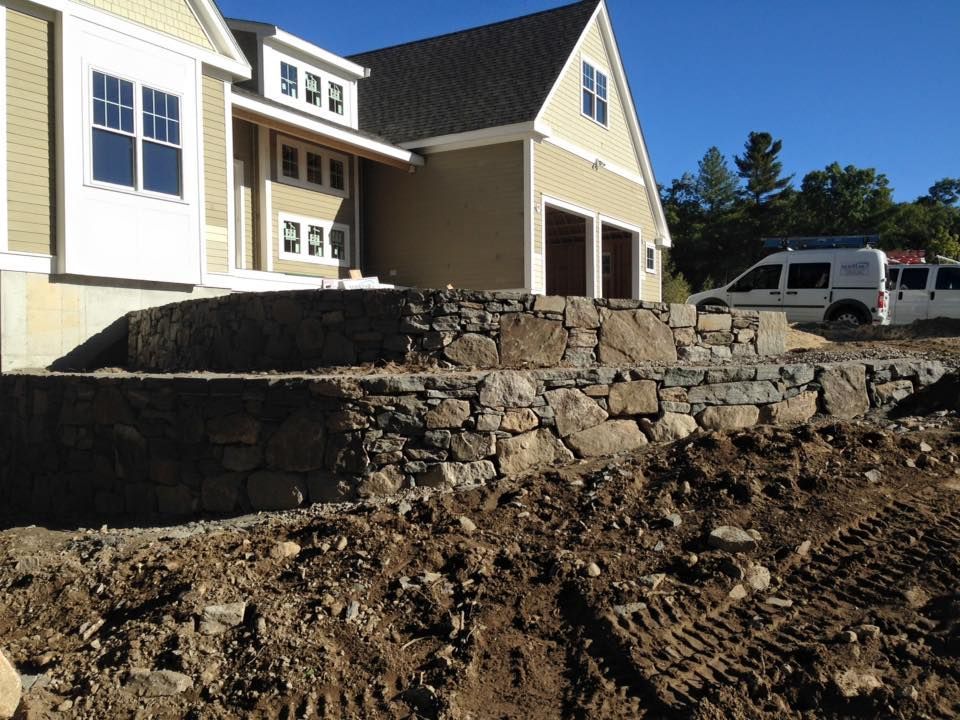 A large house with a stone wall in front of it