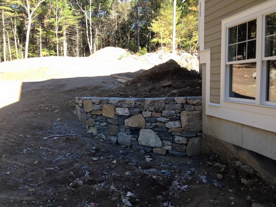 A house with a stone wall in front of it