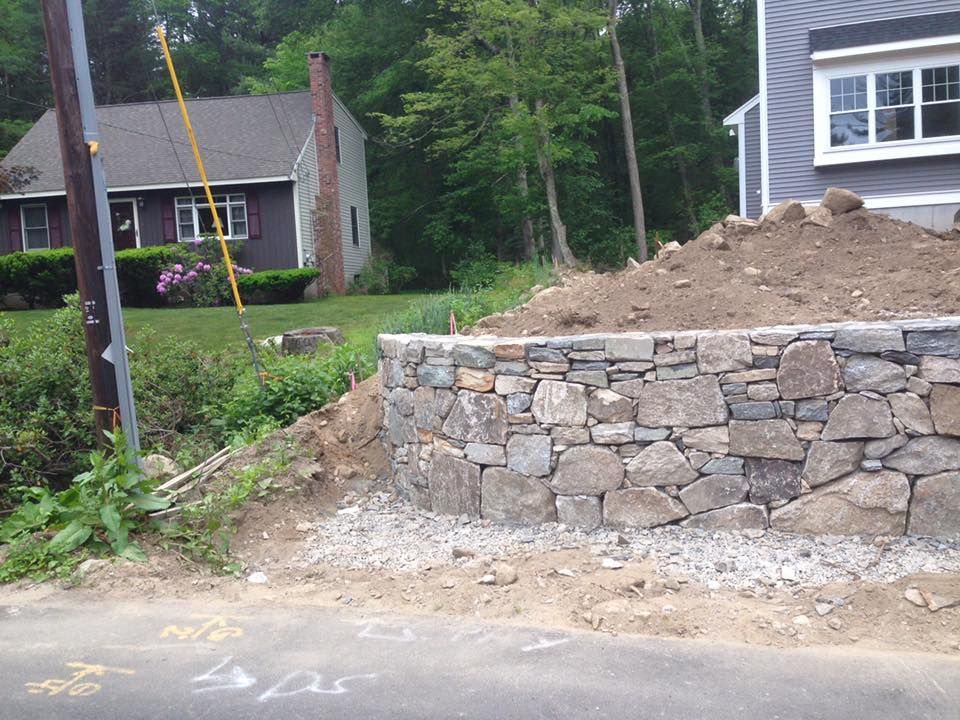 A stone wall is being built in front of a house