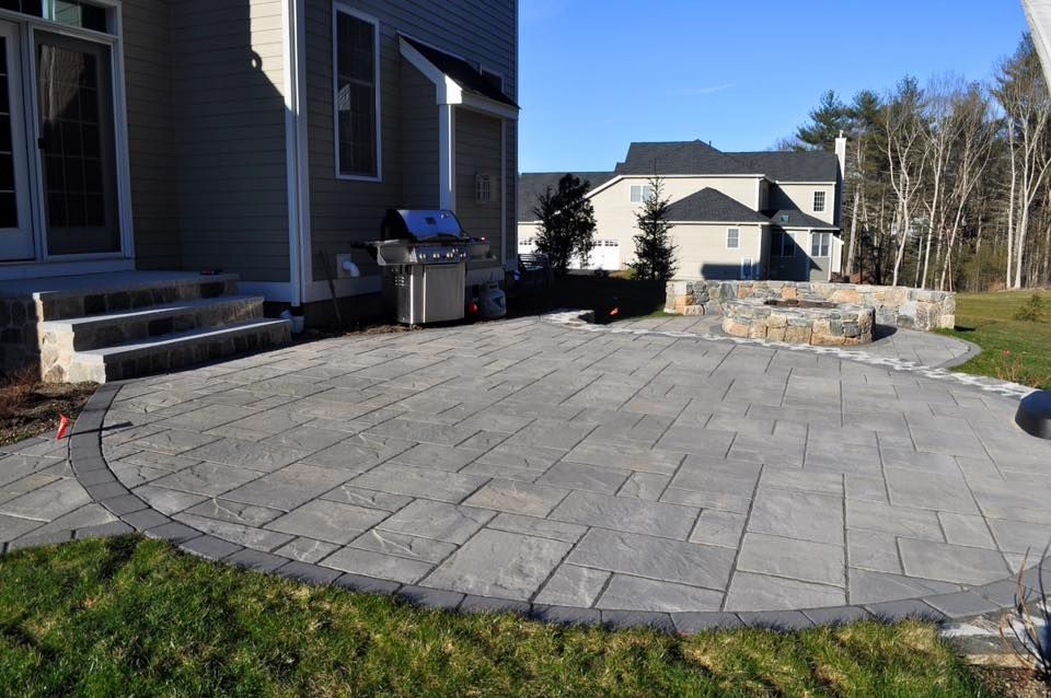 A large patio with a grill in the backyard of a house.