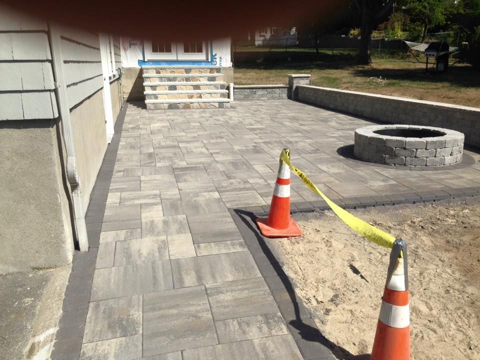 A brick walkway with a fire pit in the middle