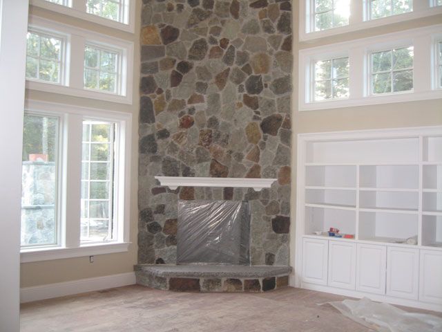 A living room with a stone fireplace and lots of windows