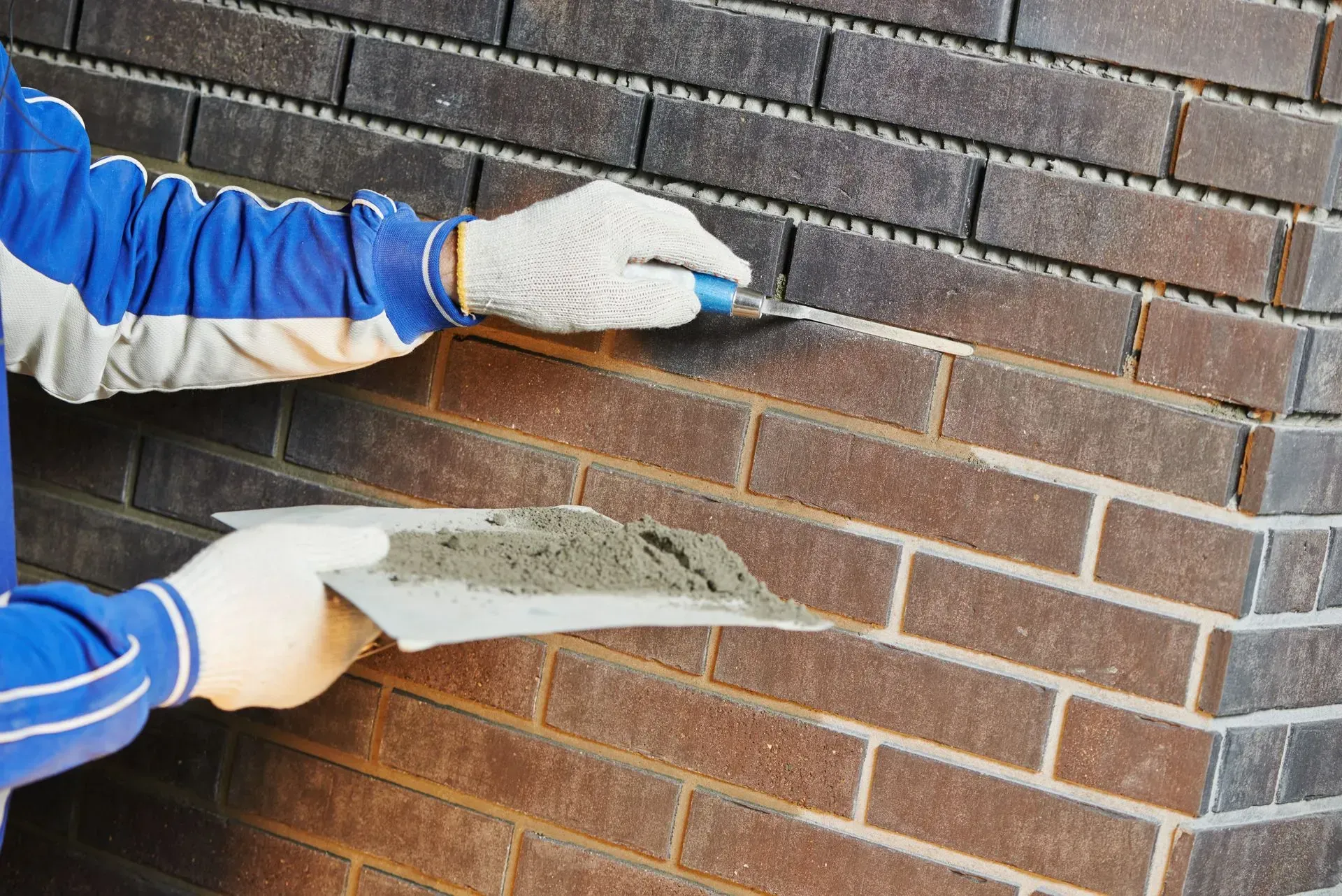 Person applying mortar to brick corner using a trowel.