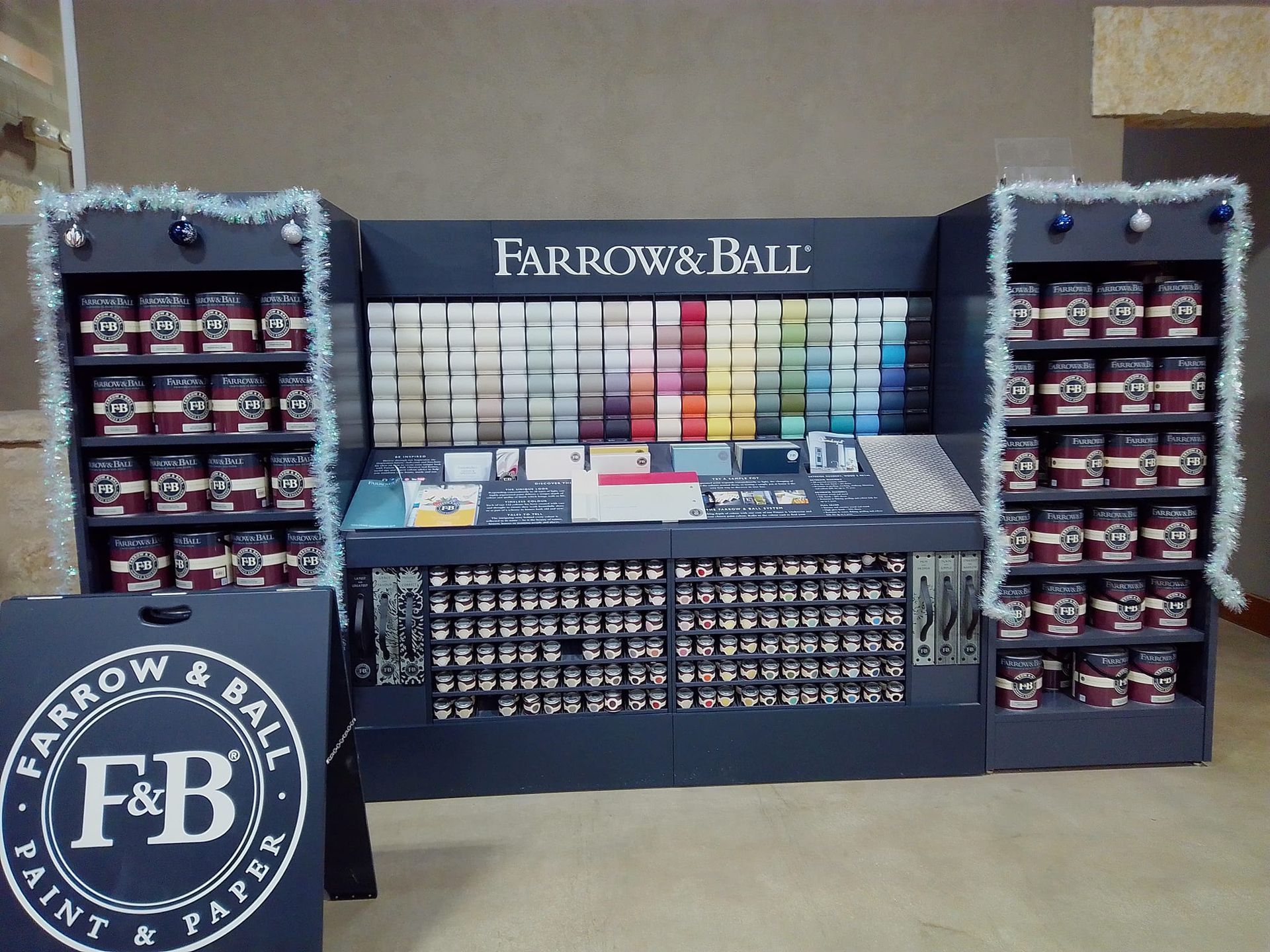 Farrow & Ball paint display with color samples and paint cans, decorated with garland.