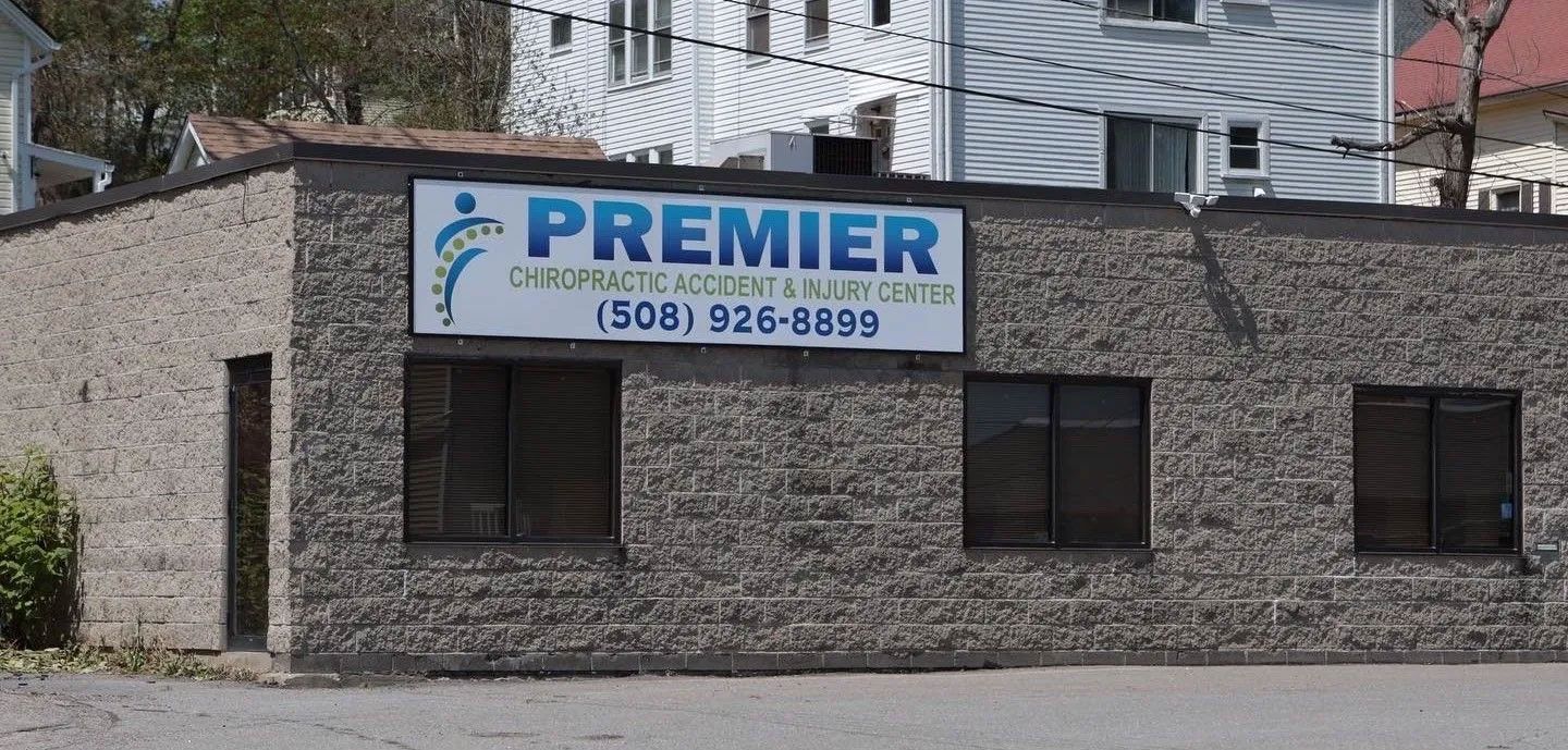Premier sign on a gray stone building with dark windows and a phone number.