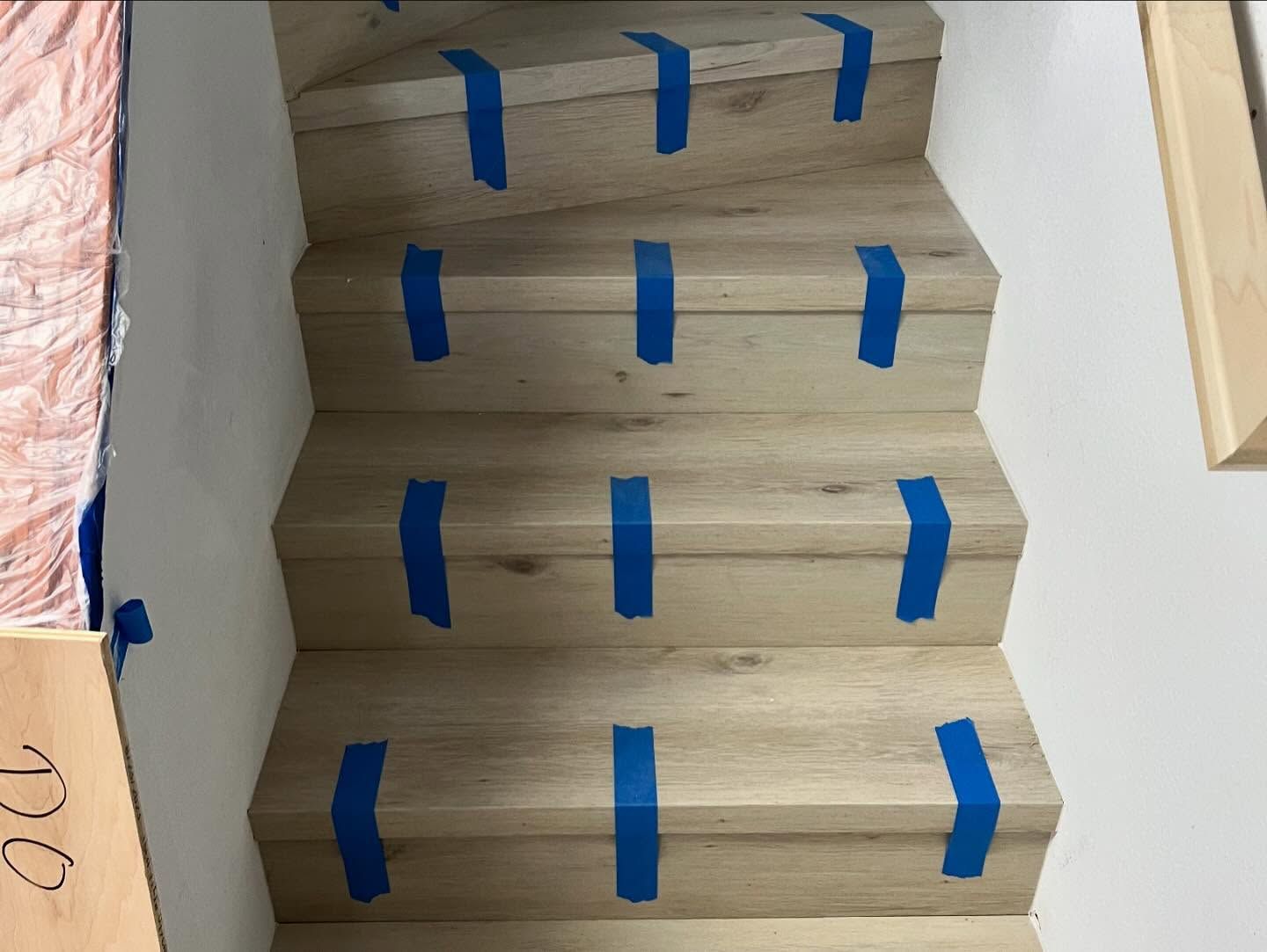 A set of wooden stairs with blue tape on them.