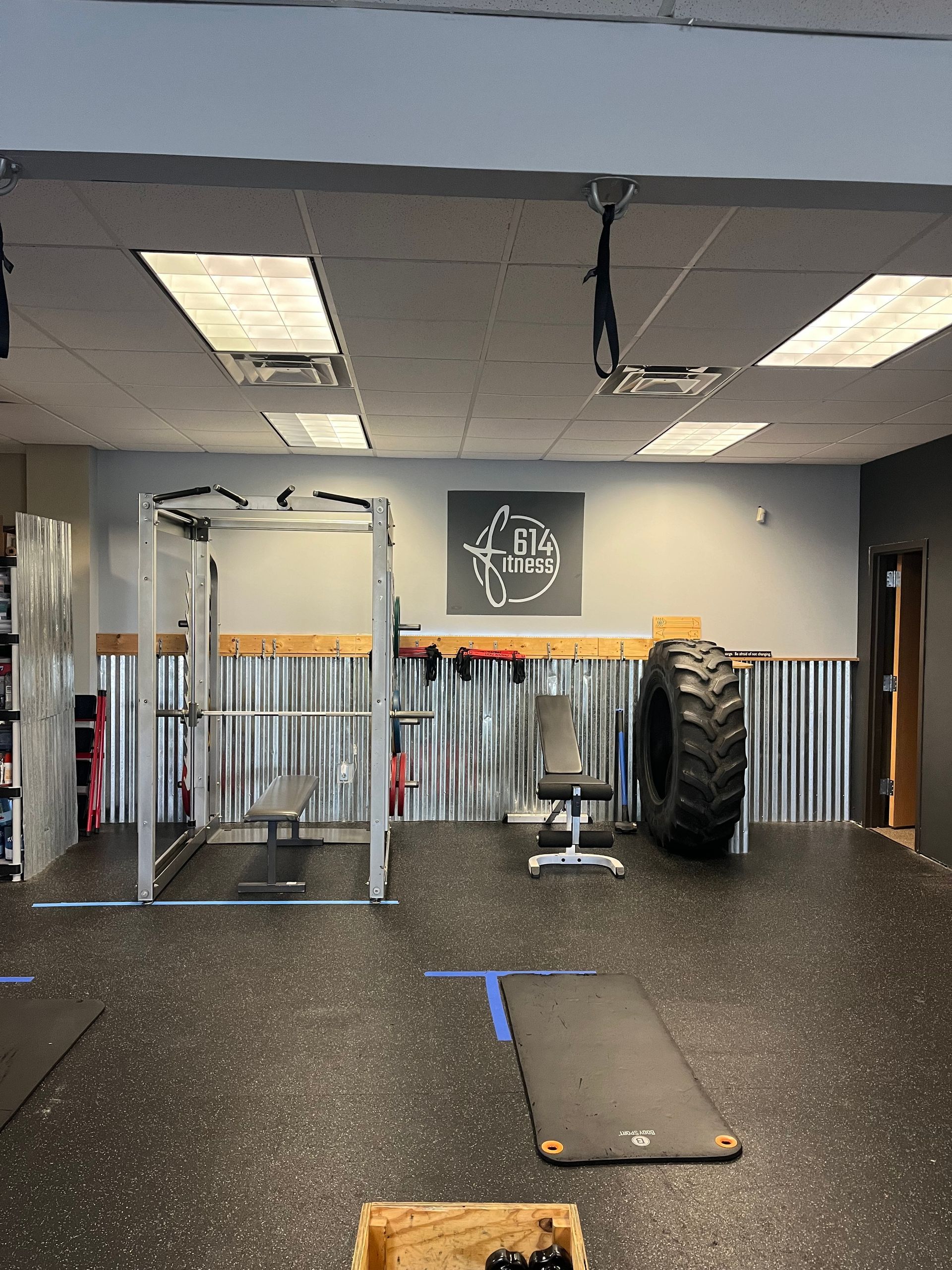Gym interior with weight equipment, including a tire and weight rack.