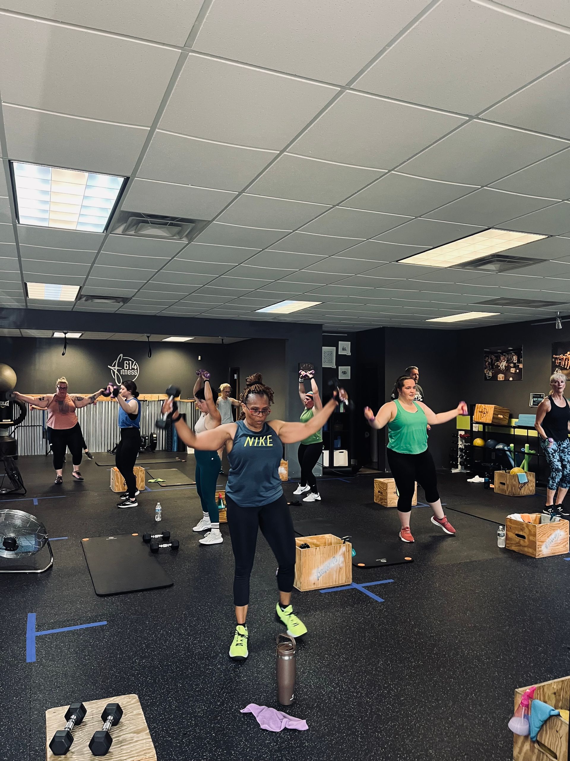 Group fitness class in a gym, participants exercising with weights.