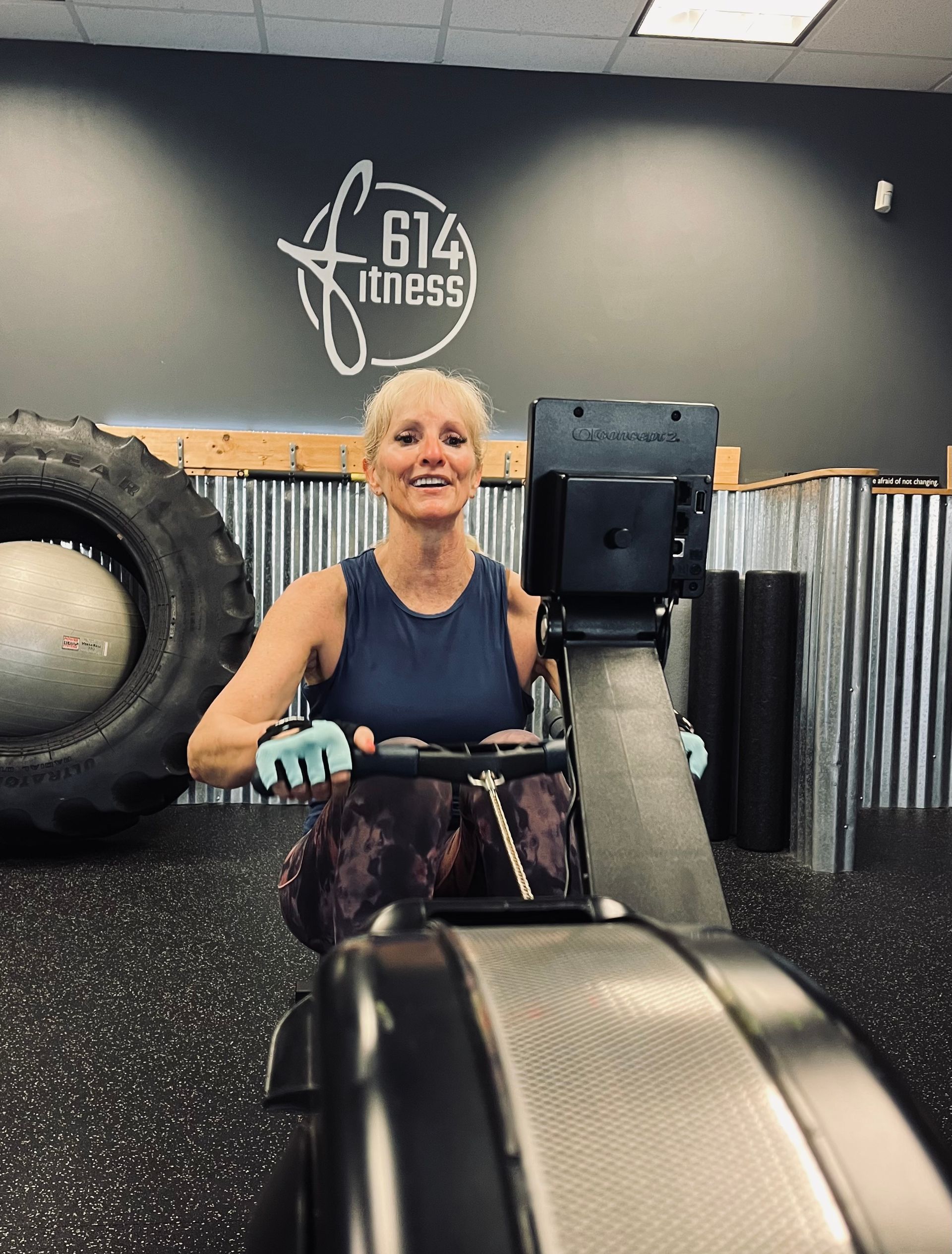 Woman smiling while using a rowing machine at a gym with the 