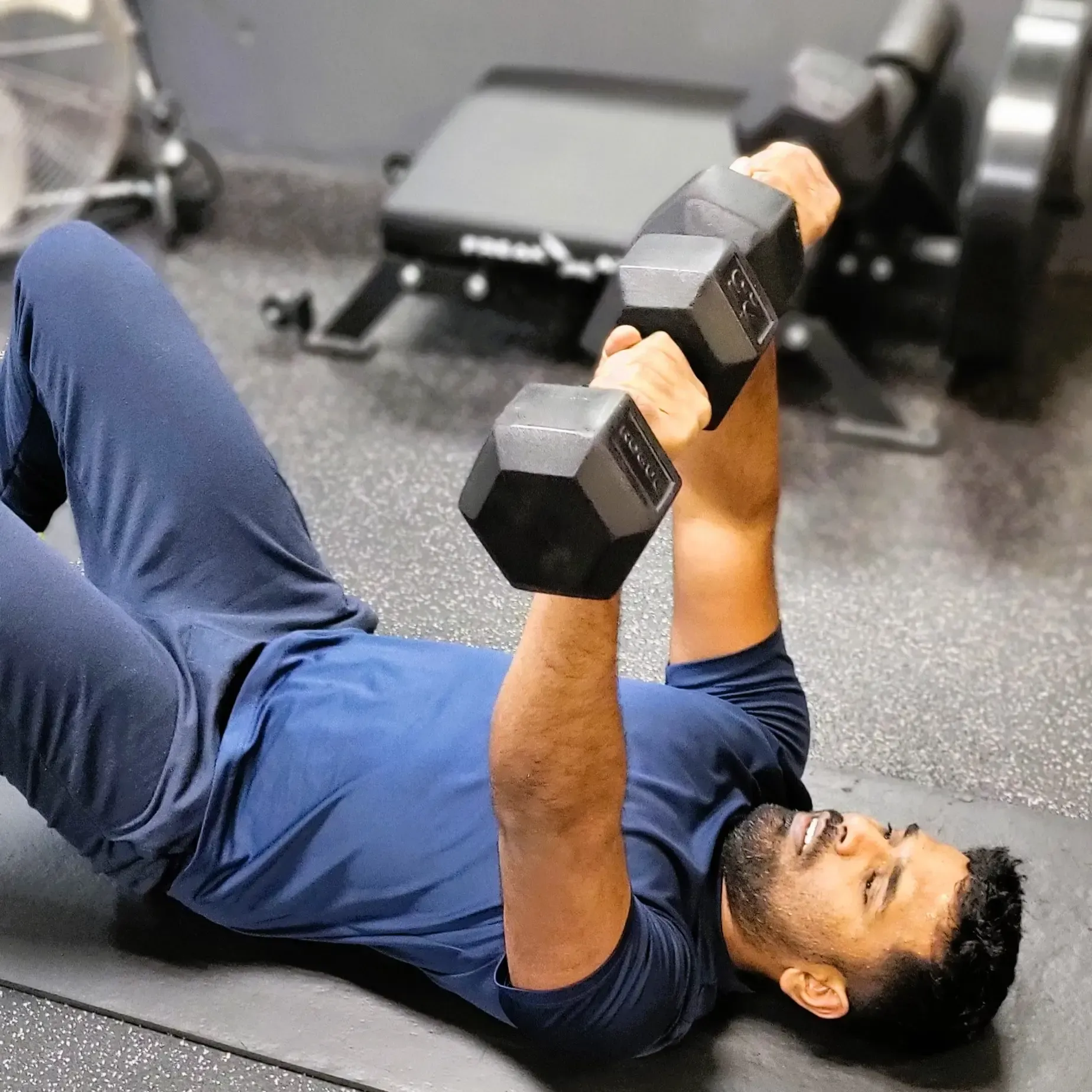 Person preparing to lift kettlebells, hands dusted with chalk, gym setting.